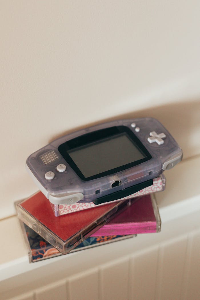 about-01 Close-up of a retro gaming console placed atop colorful cassette tapes, evoking nostalgia.