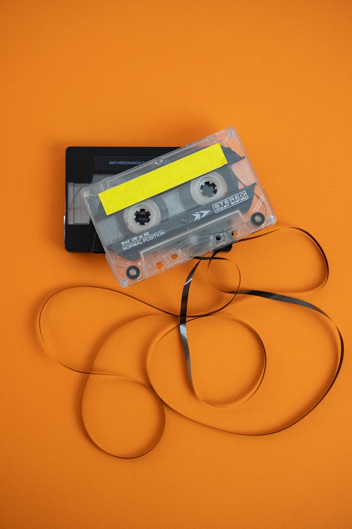 services-02 Vintage audio cassette with unraveled tape on vibrant orange background.